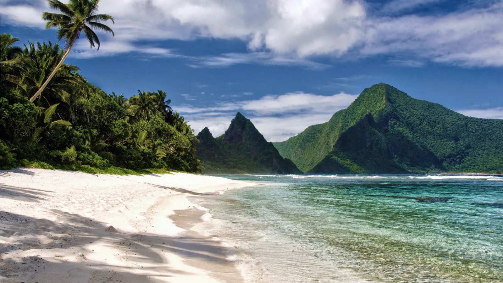 A steep green rainforest ridge falls toward the blue Pacific in the National Park of American Samoa