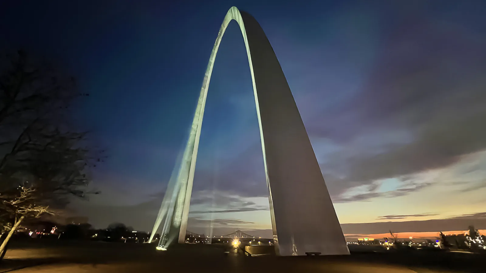The Gateway Arch rises above green park grounds and paths in downtown St. Louis