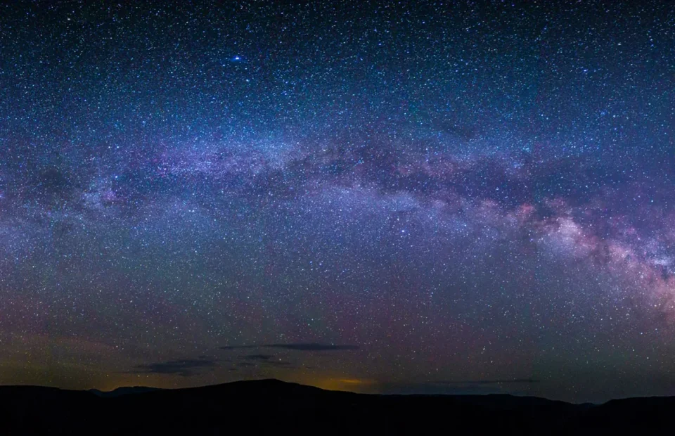 A dense field of stars and the Milky Way above the dark rim of Black Canyon of the Gunnison National Park